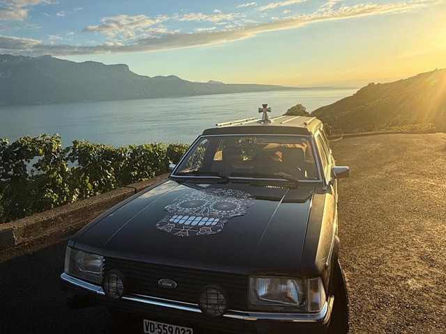 Le corbillard De la mort qui tue Corbillard De la mort qui tue avec son crâne peint sur le capot, vue sur le lac et les vignes au coucher du soleil
